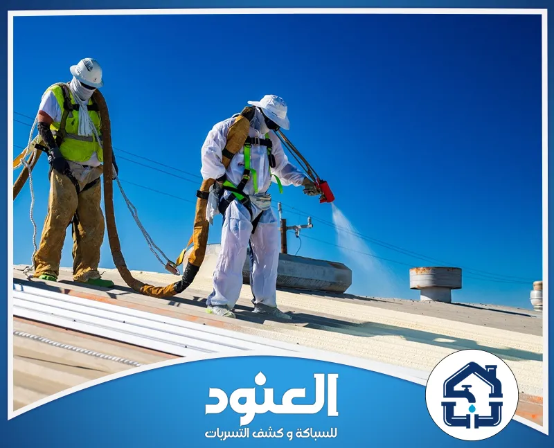 شركات عزل الشينكو بالقنفذة 0500805875 شركة العنود عاملان يرتديان ملابس واقية ويرشان العزل على سطح المبنى باستخدام معدات متخصصة.