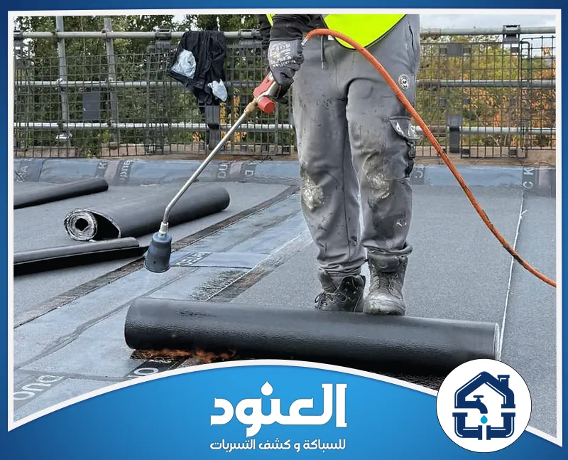 احم مبناك من العوامل الخارجية مع تركيب عزل أسطح يتم بدقة عالية. فني يعمل على فرد لفائف عازلة فوق سطح المبنى أثناء تنفيذ أعمال العزل.